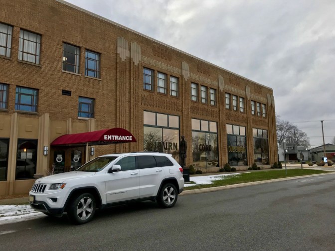 White Jeep Grand Cherokee parked in front of Auburn Cord Duesenberg Museum.