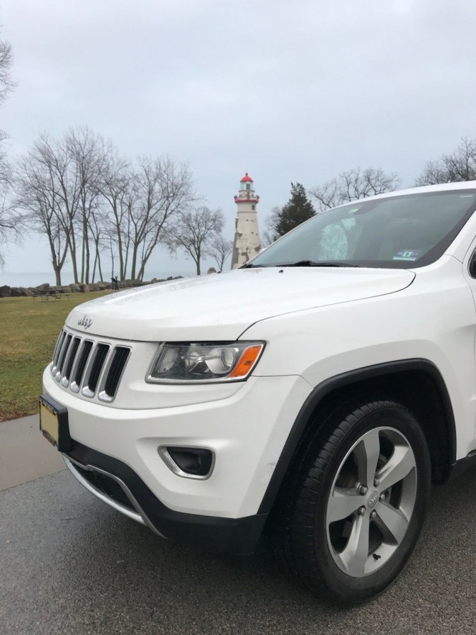 White Jeep Grand Cherokee in front of Lighthouse.