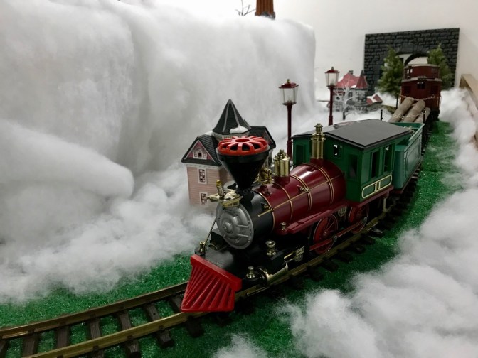 Model train running through snowy landscape.