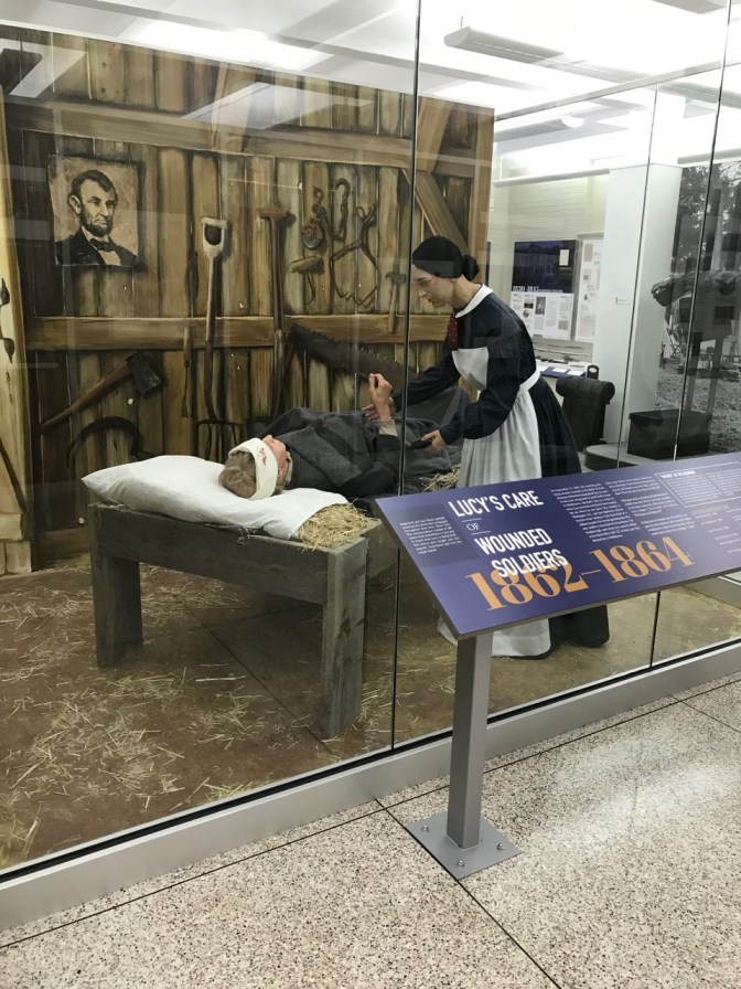Mannequins of Civil War nurse and wounded soldier, behind a glass display case.