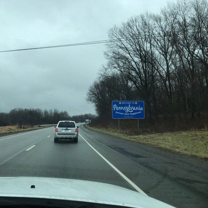 Sign by side of road that says PENNSYLVANIA PURSUE YOUR HAPPINESS.