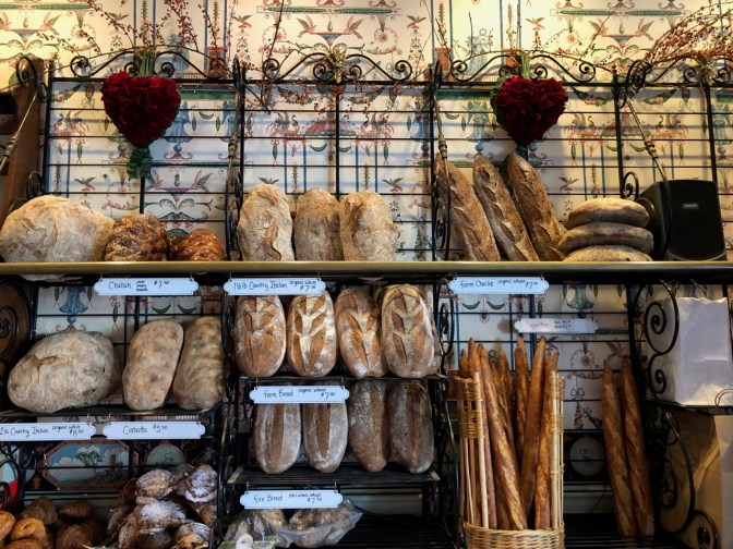 Rows of bread in baskets and on shelves in bakery.