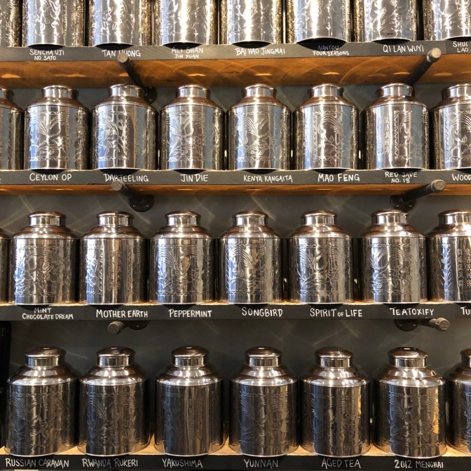Rows of metal tins holding different tea blends on shelves.
