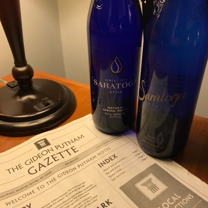 Two bottles of Saratoga spring water, and a copy of the Gideon Putnam Gazette newsletter on a desk.