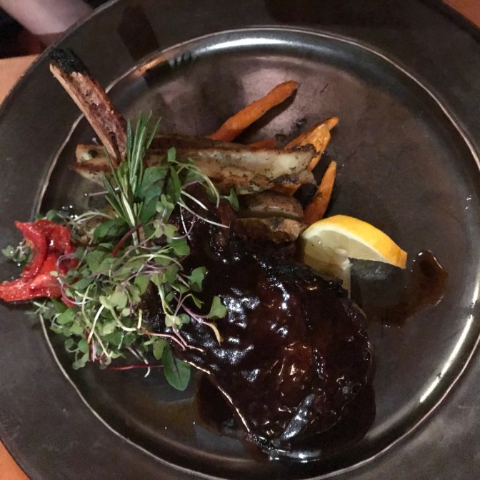 Plate with veal chop, greens, potatoes, and carrots.