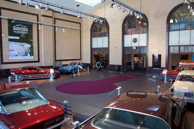 Interior atrium of Auto Museum with several cars on floor.