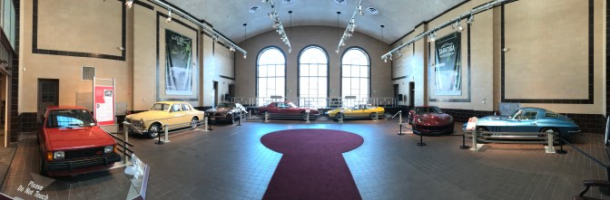 Panorama view of seven classic cars in hall's atrium.