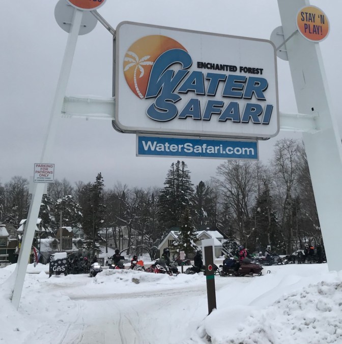 Row of snow mobiles beneath ENCHANTED FOREST WATER SAFARI sign.