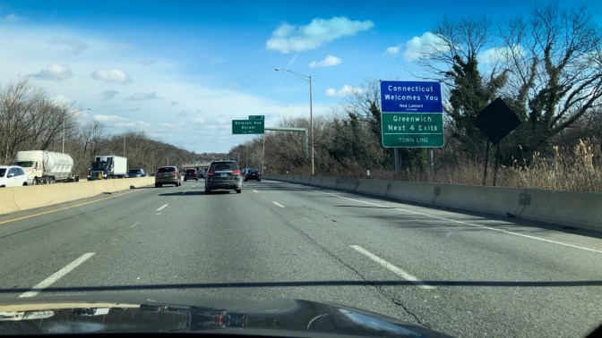 I-95 northbound, with traffic ahead, and sign by side of road saying CONNECTICUT WELCOMES YOU.