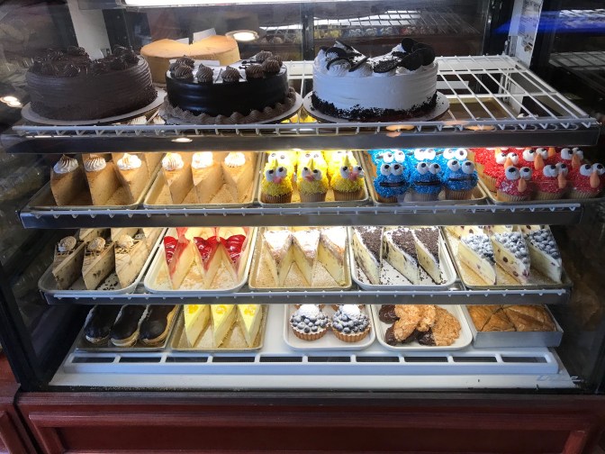 Display case with numerous cakes, cookies, pies, and cupcakes.
