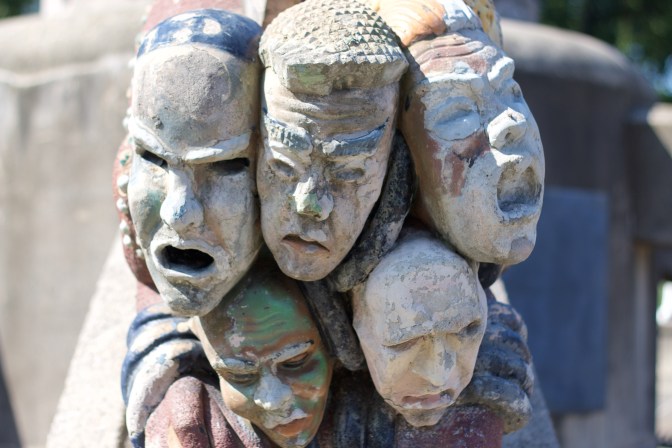 Five grotesque sculpture faces on fountain.
