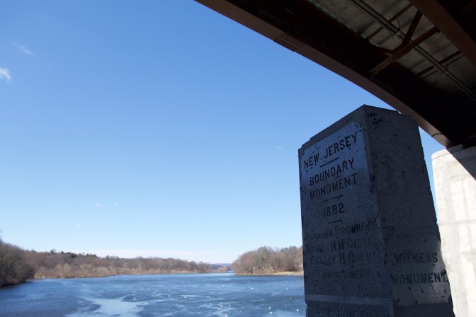 Beneath a bridge is a monument, inscribed with NEW JERSEY BOUNDARY MONUMENT 1882.