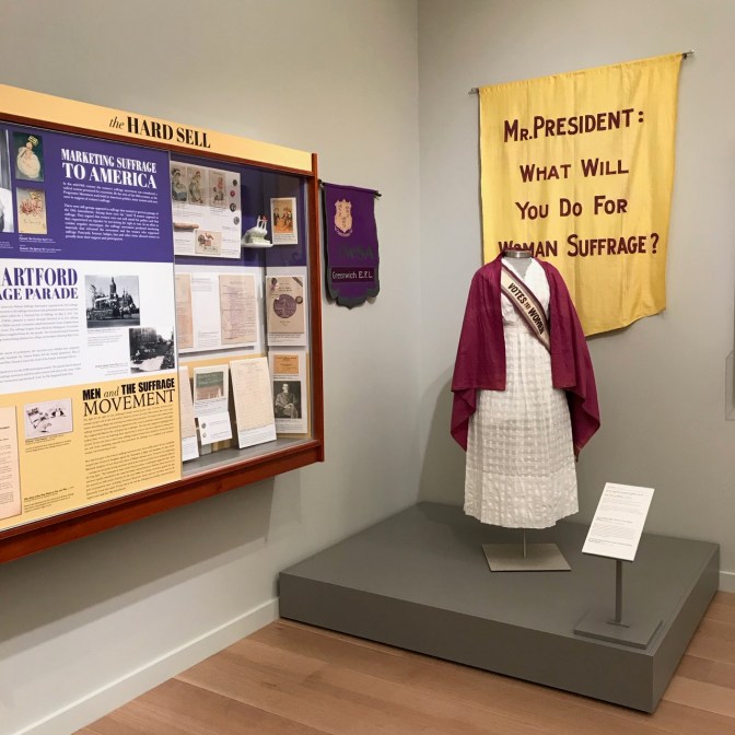 Exhibit on women's suffrage, including an outfit worn by a suffragette and information about the women's right to vote movement.