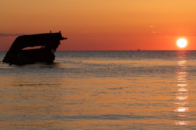 Concrete ship off Sunset Beach in Cape May, with setting sun in background.