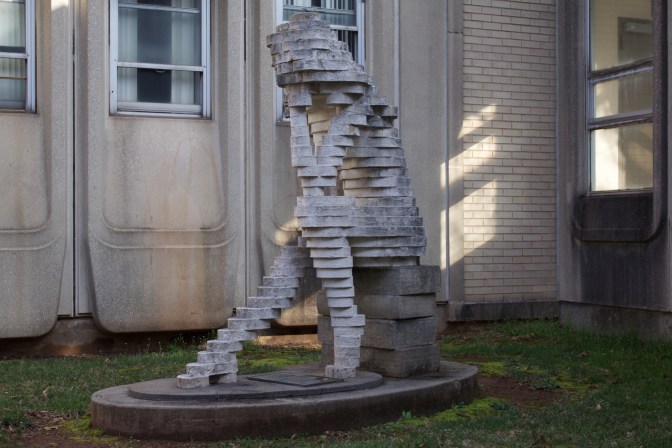 Sculpture of The Thinker, in block form, seated on books.