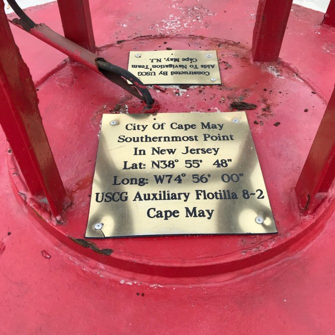Brass plaque on base of red buoy, inscribed with CITY OF CAPE MAY SOUTHERNMOST POINT IN NEW JERSEY LAT: N38* 55' 48" LONG: W74* 56' 00" USCG AUXILIARY FLOTILLA 8-2 CAPE MAY