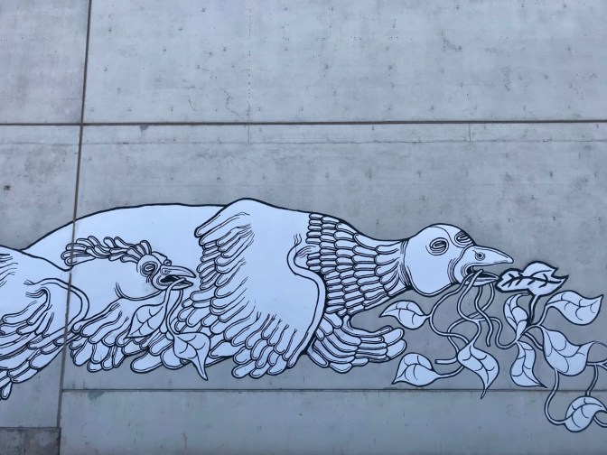 Mural of two grotesque birds in flight, with vines in their mouths.