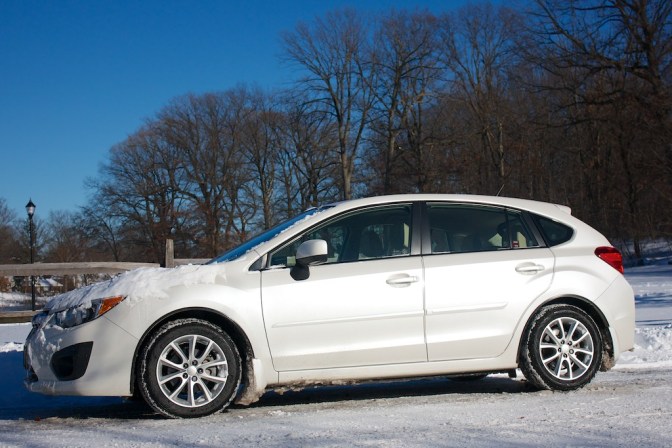 2013 white Subaru Impreza, on a snow-covered road.