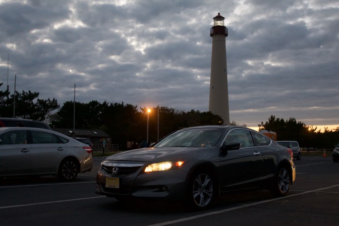 2012 Honda Accord coupe parked in front of Cape May Lighthouse at night, with lights on in car.