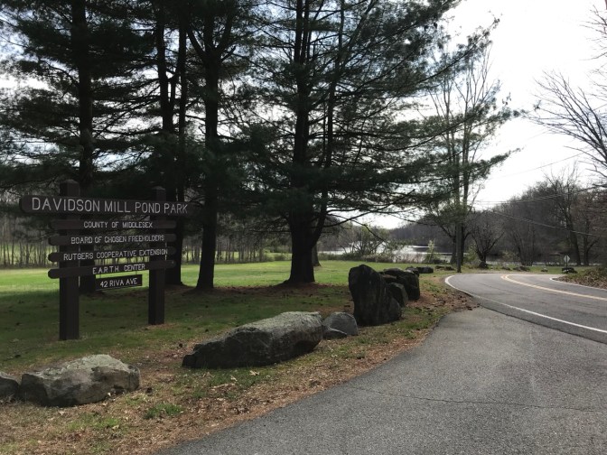 Entrance to Davidson Mill Pond Park, with wooden sign indicating name of park.