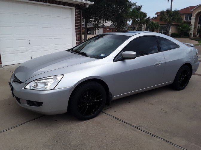 2003 Honda Accord coupe, in silver, parked in driveway in front of close garage.