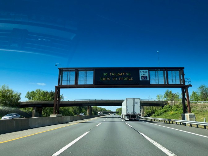 Sign above NJ Turnpike saying NO TAILGATING CARS OR PEOPLE.