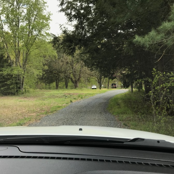 View of gravel road to parking lot, through windshield of Jeep Grand Cherokee.