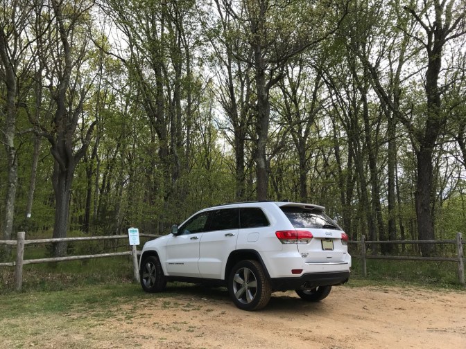 White Jeep Grand Cherokee parked in dirt lot.