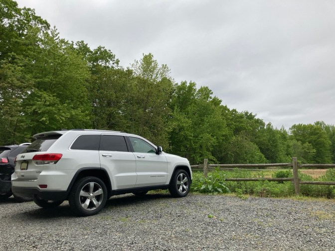 White Jeep Grand Cherokee parked in gravel lot.