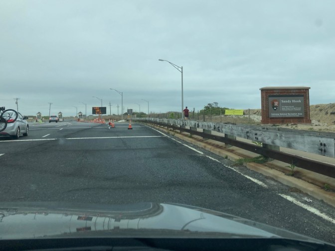 Entrance to Sandy Hook, with sign on right saying SANDY HOOK and the National Park Service Badge.