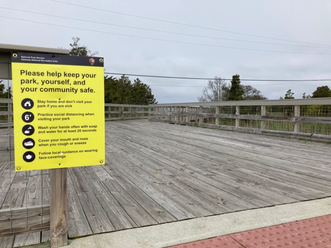 Sign by entrance to board walk with social distancing rules.