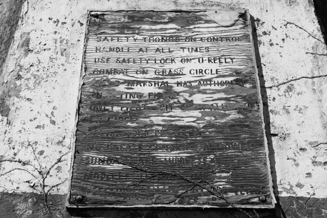 Decaying wooden plaque with information for flying club.
