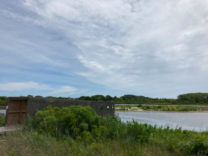 Camoflauged blind building for spotting birds on meadow.