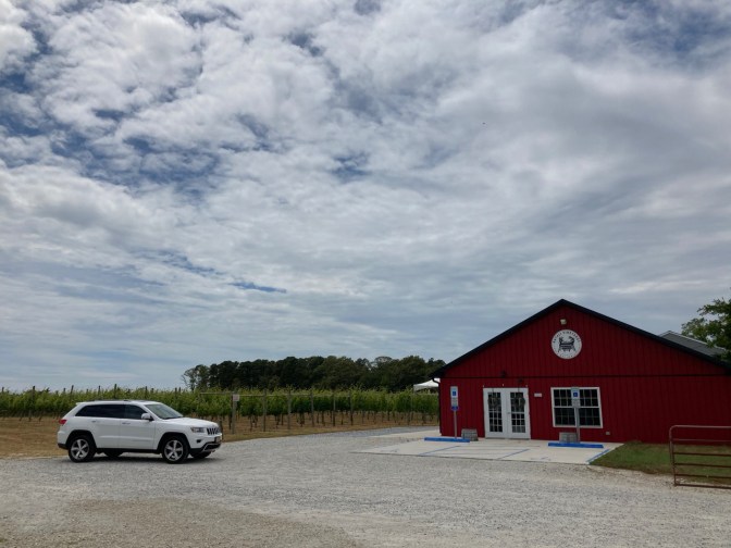 White Jeep Grand Cherokee parked in front of Natali Vineyards main building.