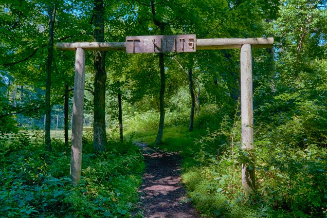 Entrance to tennis courts, with the word T_NNIS on a wooden plank above the entrance.