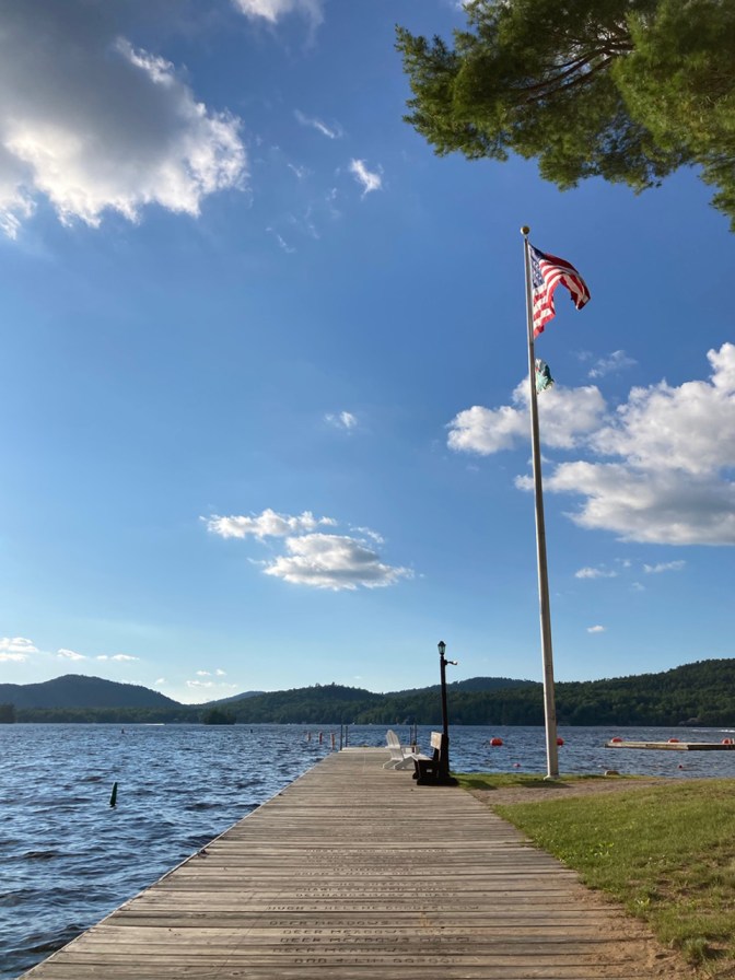 US flag atop flagpole beside dock along Fourth Lake.