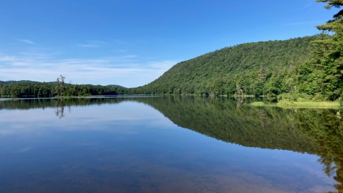 View of Moss Lake, with a reflection of the mountain and shoreline in the lake.