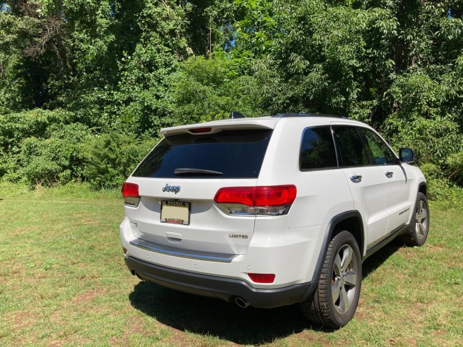 White Jeep Grand Cherokee parked on a grassy field.