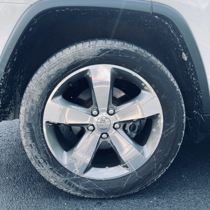 Muddy tire on white Jeep Grand Cherokee.