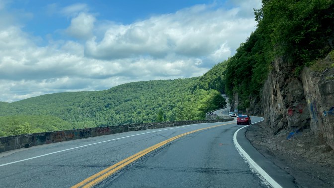 View of Route 97 through mountains, with cliffs on right side of road.