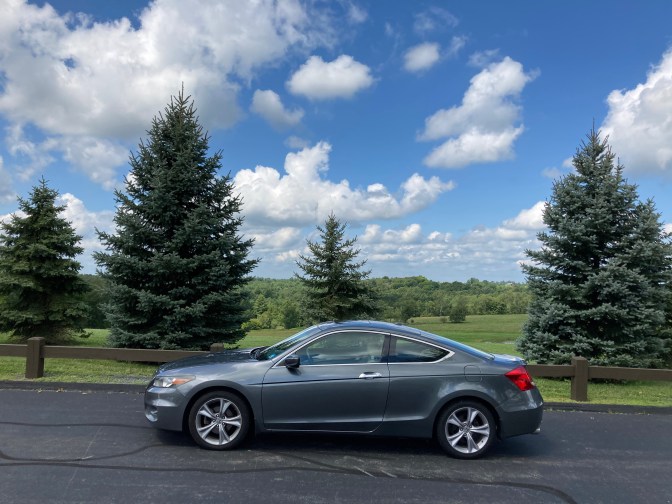 2012 Honda Accord coupe, parked in front of tree-lined hills.