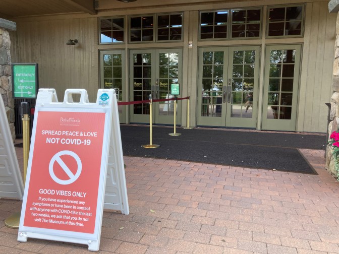 Sign outside of entrance doors to Bethel Woods Center, that says SPREAD PEACE & LOVE NOT COVID-19.