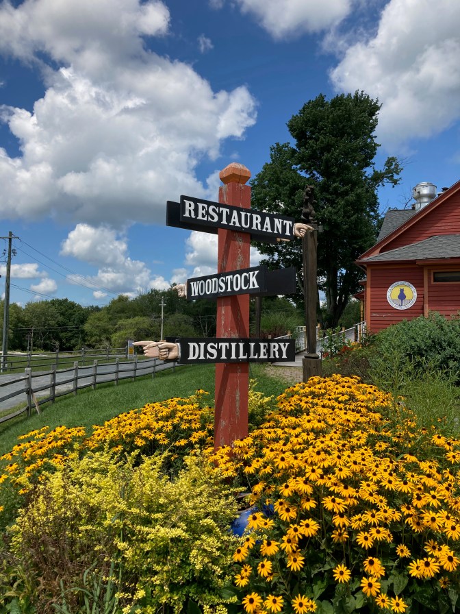 Three-way sign indicating Restaurant, Woodstock, and Distillery.