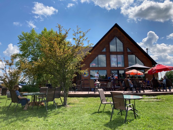Exterior distillery, with people sitting on patio.