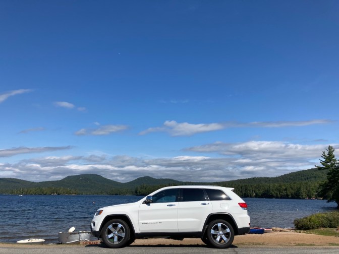 White Jeep Grand Cherokee parked in front of Blue Mountain Lake.