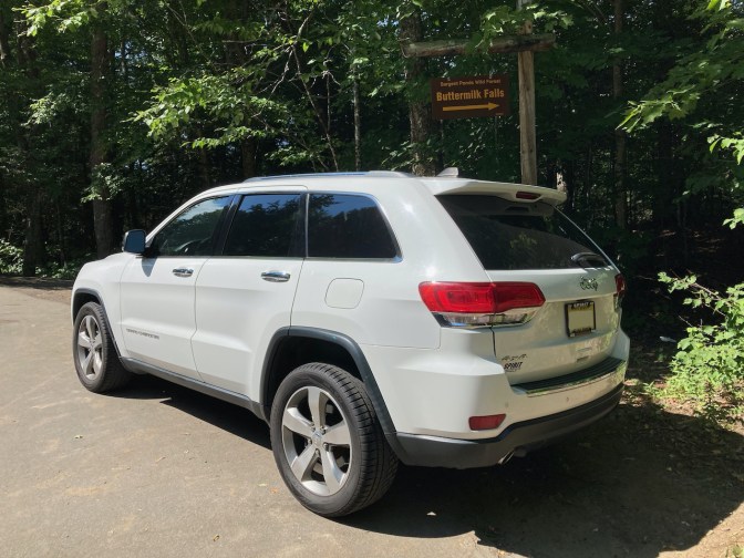 White Jeep Grand Cherokee in front of sign that says BUTTERMILK FALLS