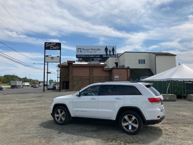 White Jeep Grand Cherokee parked in front of Satin Dolls club.