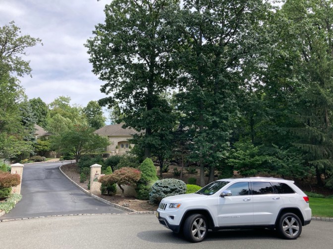 White Jeep Grand Cherokee parked in front of mansion.