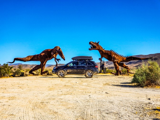 Acura MDX in front of two dinosaur sculptures.