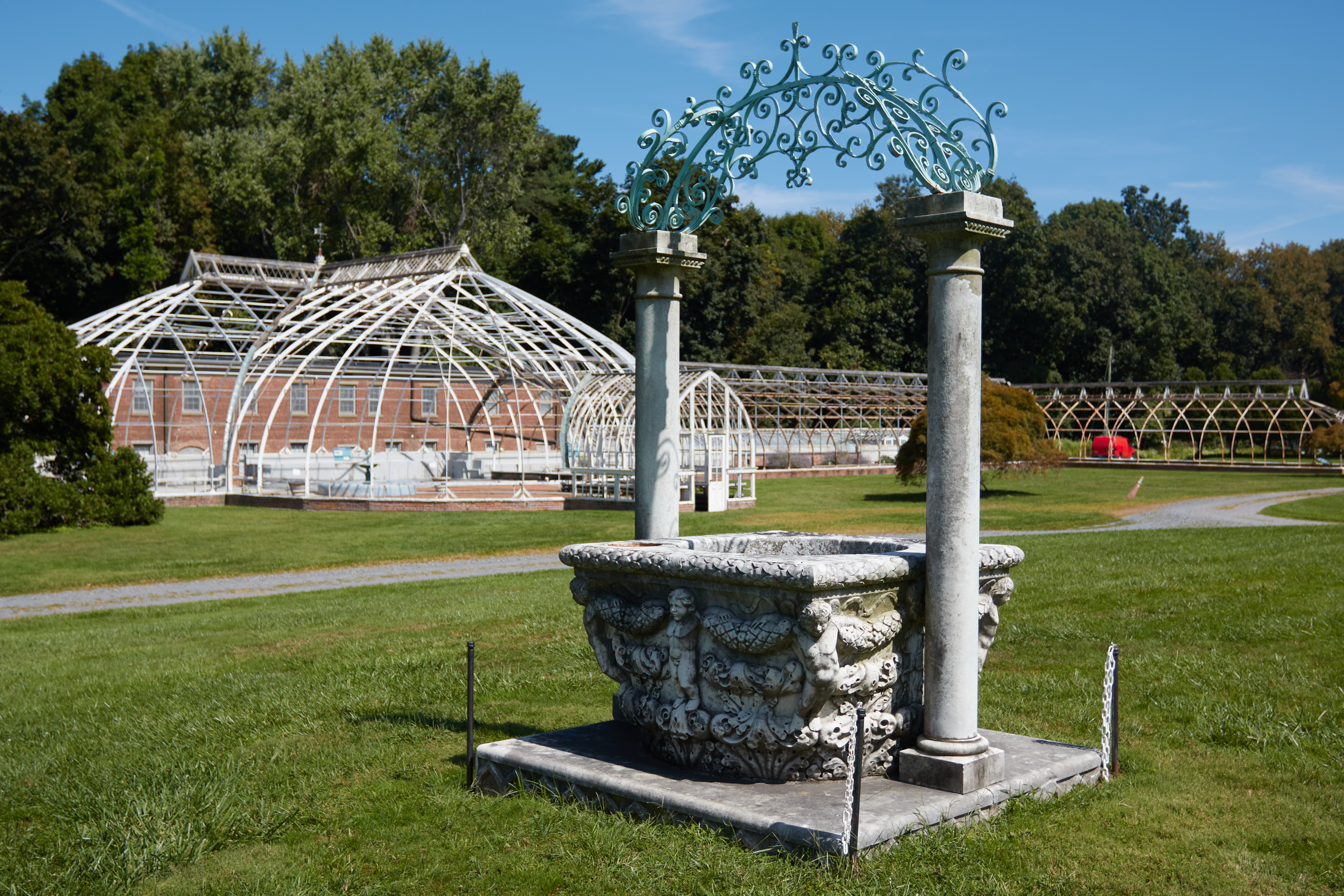 Marble fountain in front of greenhouse.